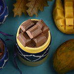 Container filled with chocolate bars on a blue background with autumn leaves and Mangoes.