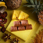 Chocolate bars on a yellow surface with pineapple slices and decorative elements.